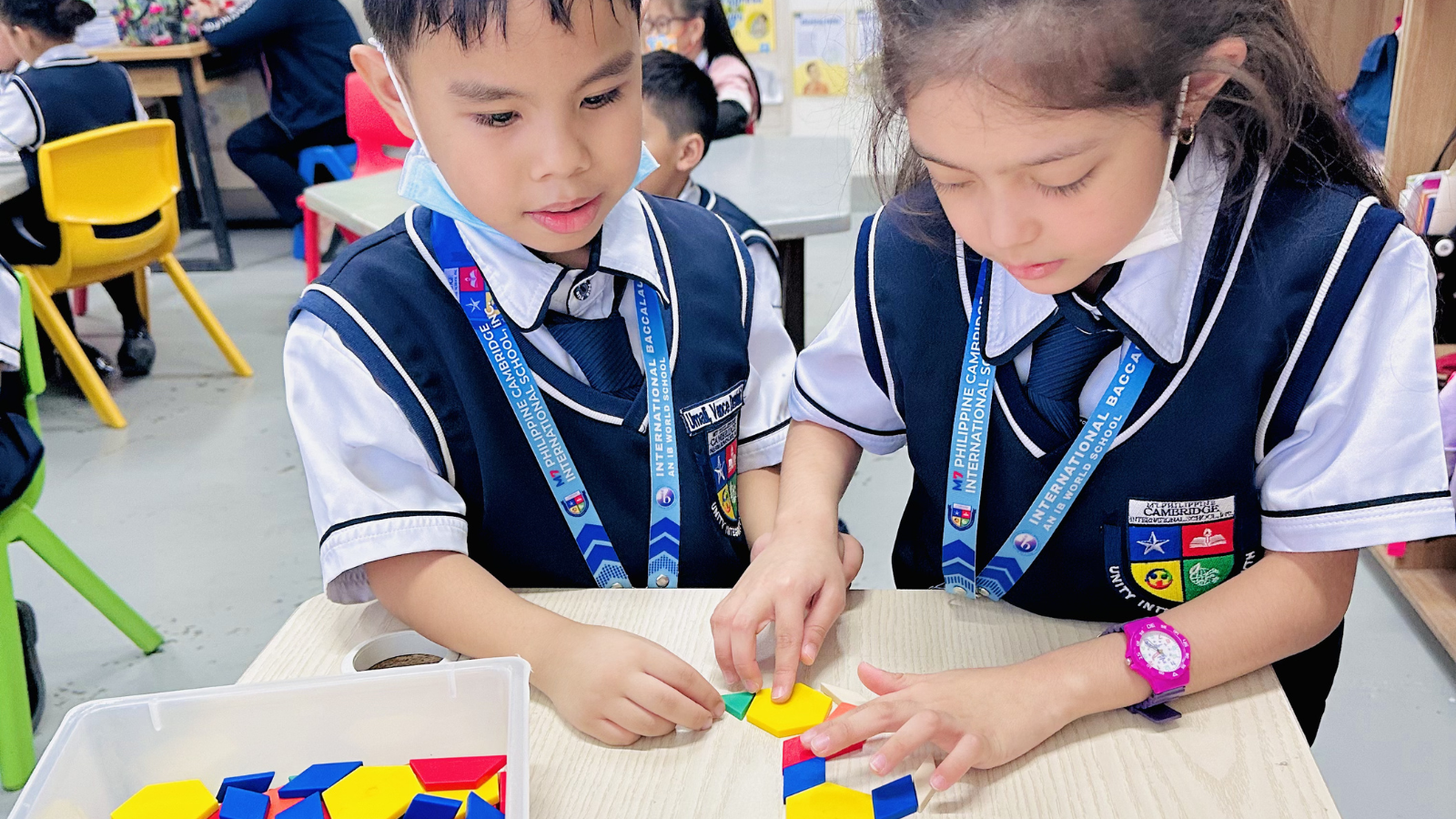 Two PYP students, a boy and a girl, collaborating to complete a pattern activity, showing teamwork and problem-solving skills.