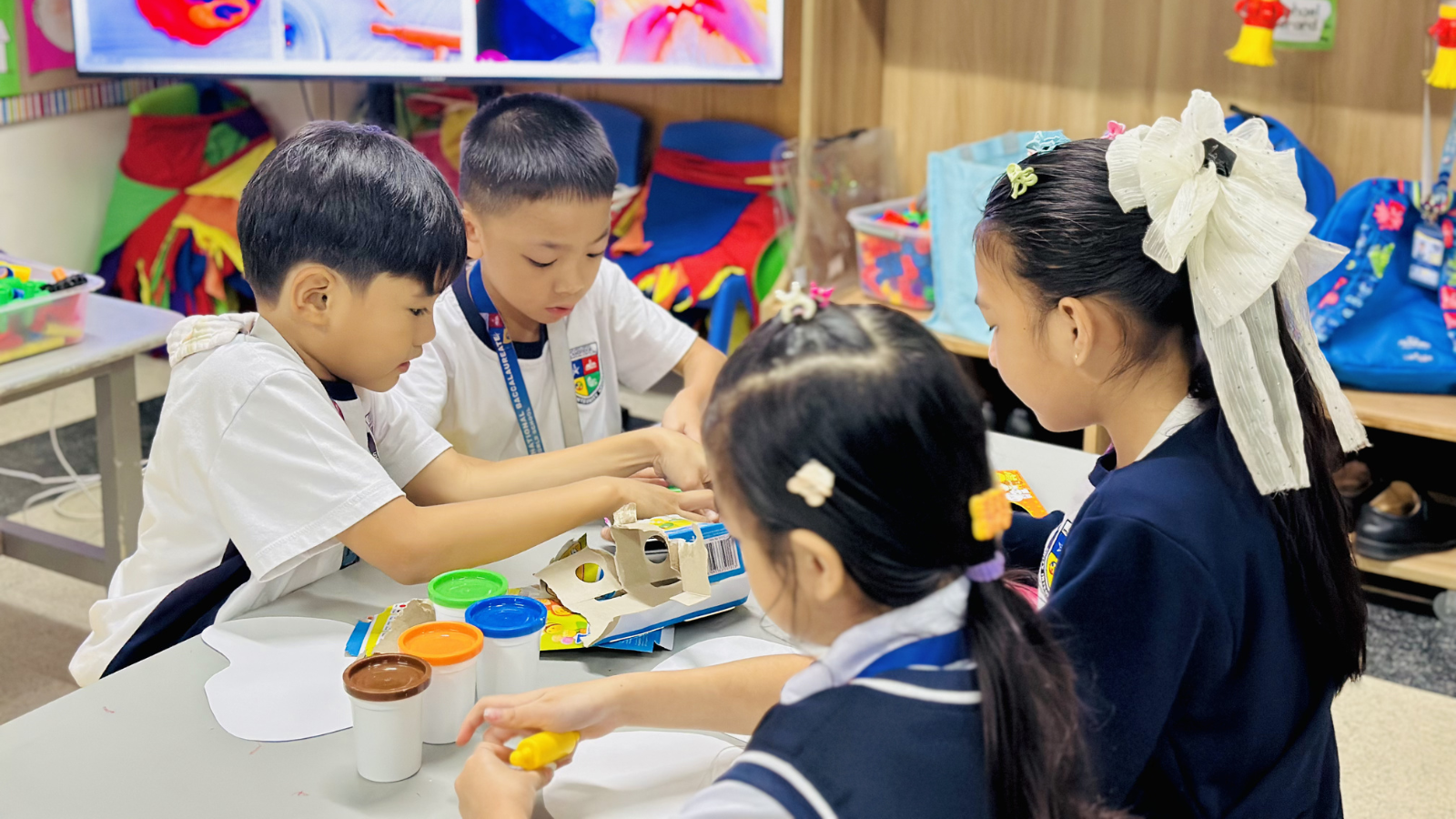 Four PYP students working together on a classroom project, engaged in collaborative learning and sharing ideas.